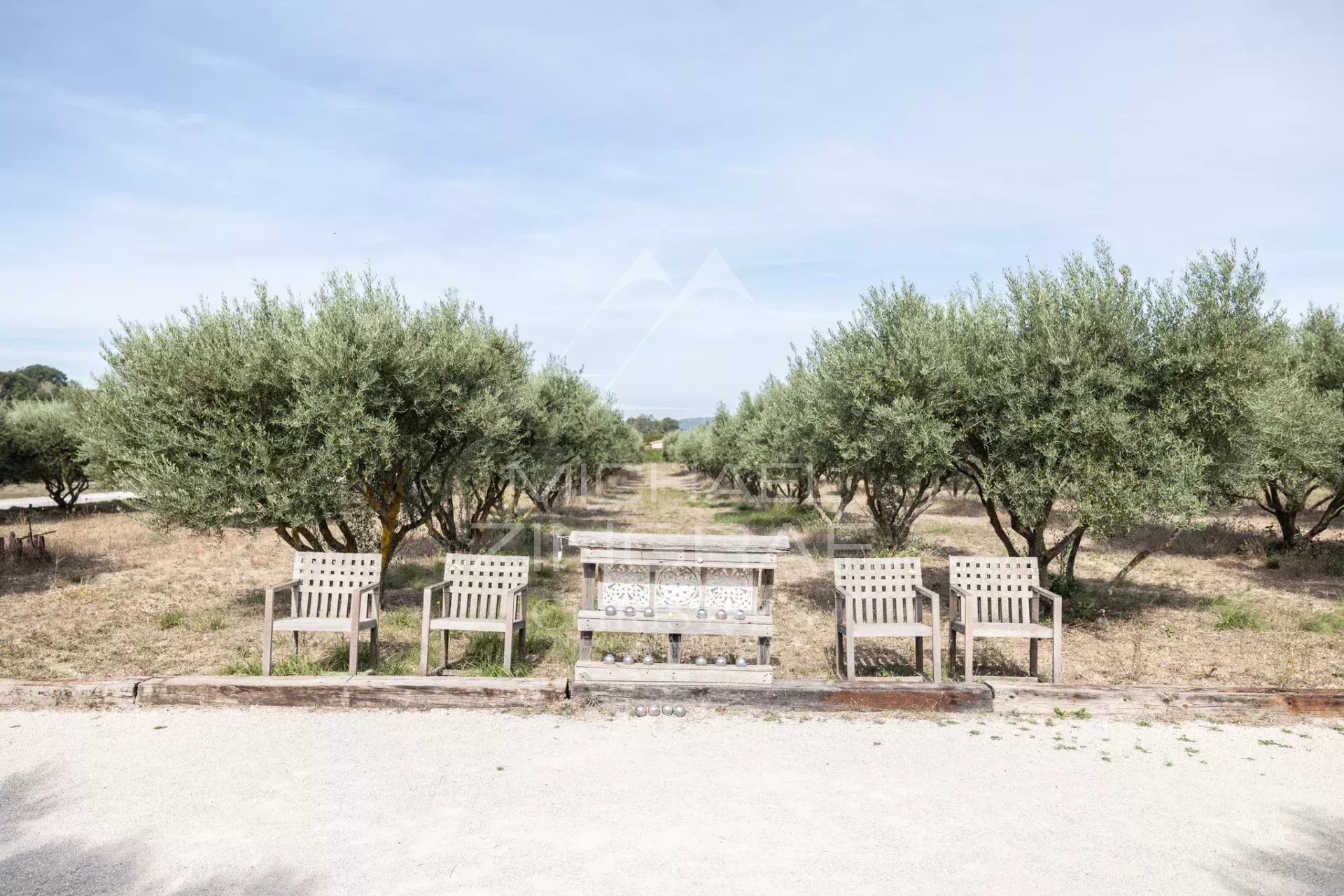 Garden of a Provencal farmhouse in Oppède View of a garden with wooden benches and olive trees in Oppède.