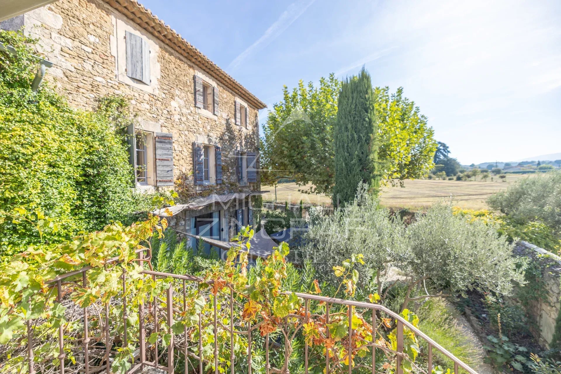 Provençal farmhouse in Oppède Provençal stone farmhouse with gîtes and guest rooms in Oppède, surrounded by greenery and fields.