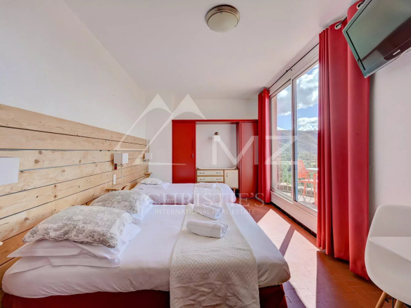 Chambre d'hôtel confortable avec vue panoramique, murs en bois et grandes fenêtres.