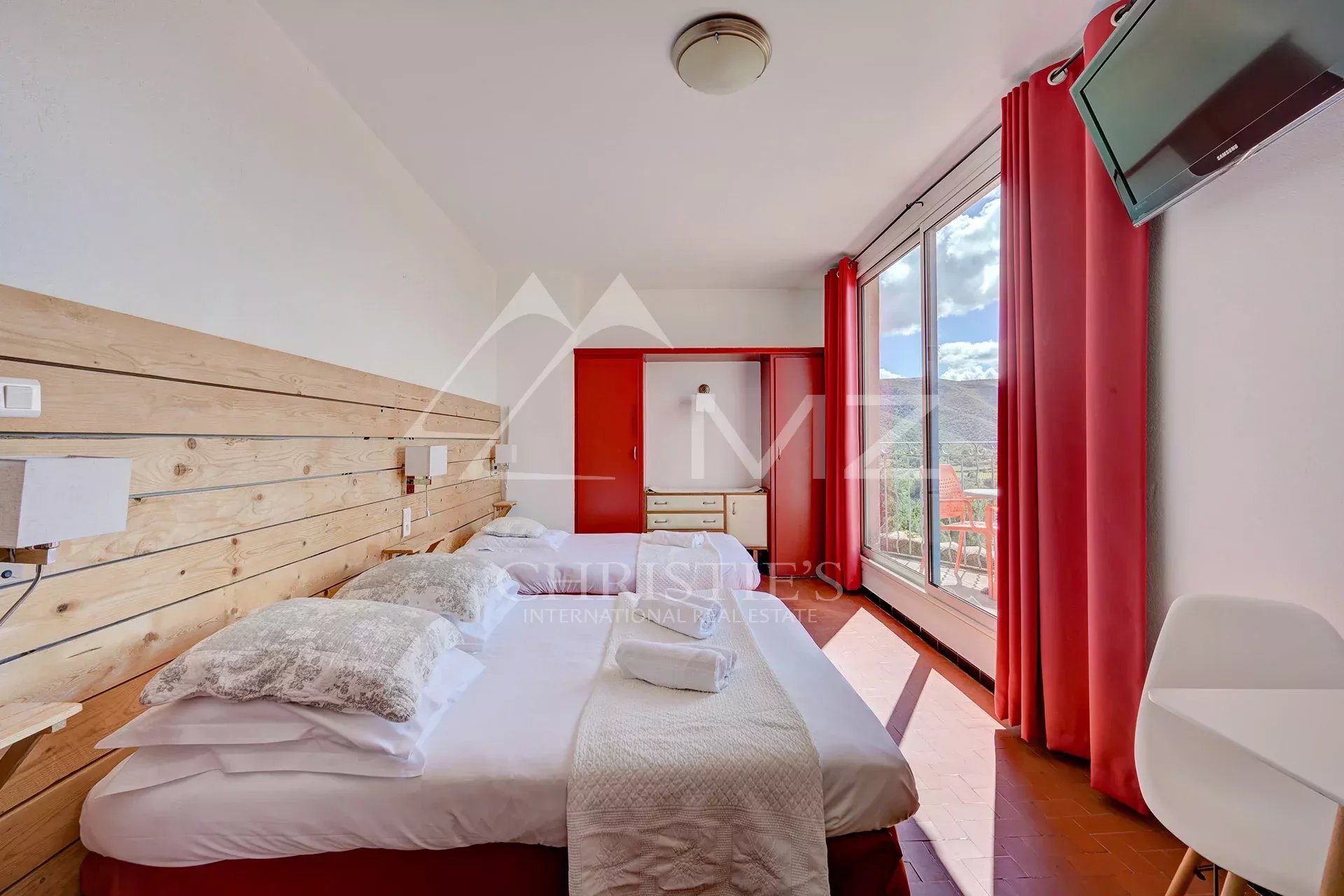 Chambre d’hôtel au Luberon Chambre d'hôtel confortable avec vue panoramique, murs en bois et grandes fenêtres.