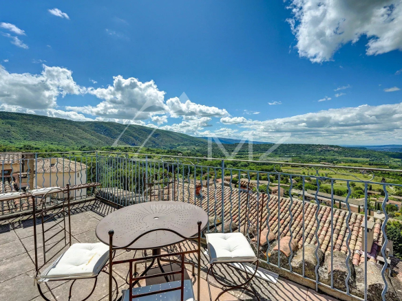 Terrasse avec vue panoramique sur les collines du Luberon depuis un hôtel à Bonnieux.