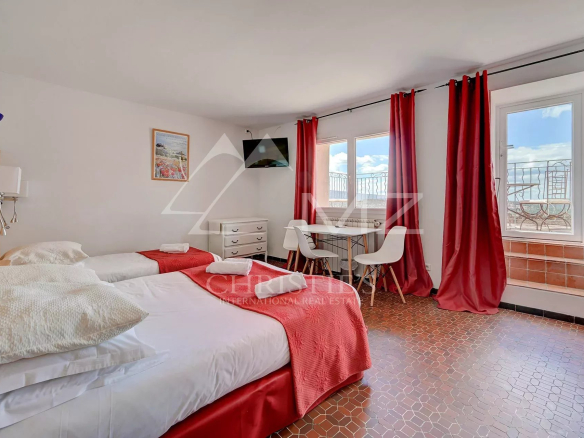 Chambre d'hôtel avec deux lits simples, table et chaises, vue sur l'extérieur à Bonnieux.