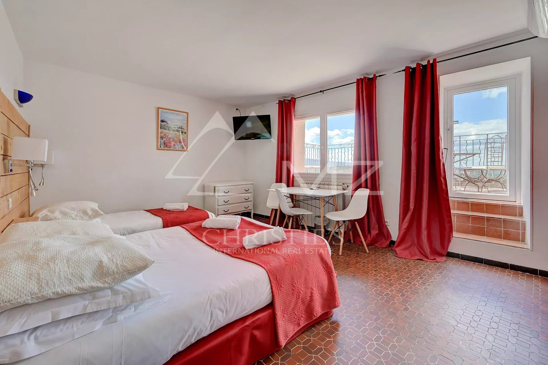 Chambre d’hôtel à Bonnieux Chambre d'hôtel avec deux lits simples, table et chaises, vue sur l'extérieur à Bonnieux.