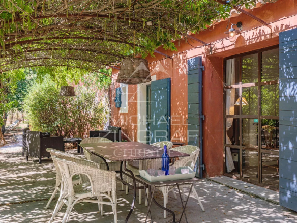 Terrasse d'une maison à Roussillon avec mobilier de jardin et végétation luxuriante.