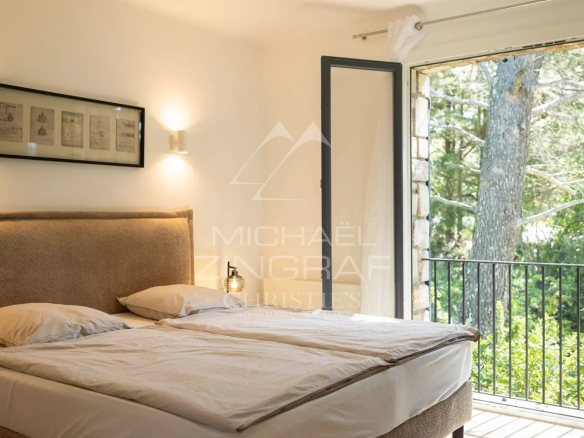 Chambre d'une maison en pierre à Roussillon avec balcon et vue sur la nature.