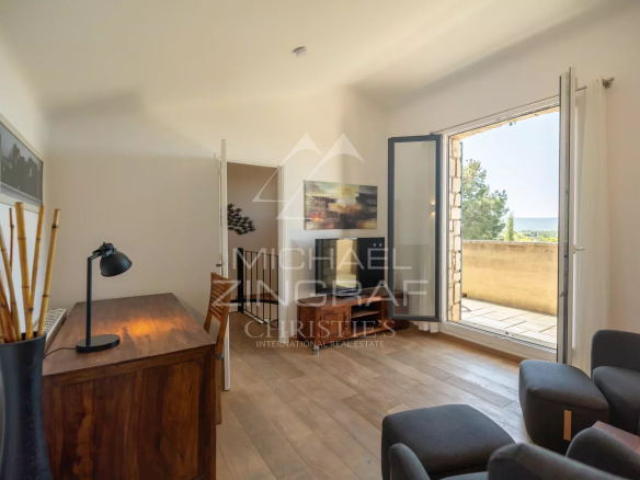 Intérieur d'une maison en pierre à Roussillon avec vue panoramique, mobilier moderne et lumière naturelle.