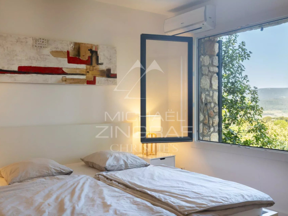 Chambre d'une maison en pierre à Roussillon avec vue sur la nature.