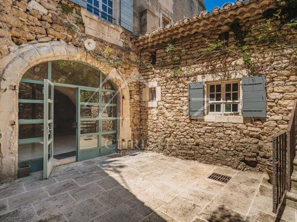 Entrance to a stone building with a commercial space and an apartment in Ménerbes.