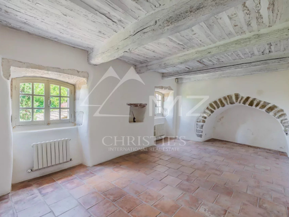Interior of a renovated commercial space with exposed beams and terracotta floor in Ménerbes.