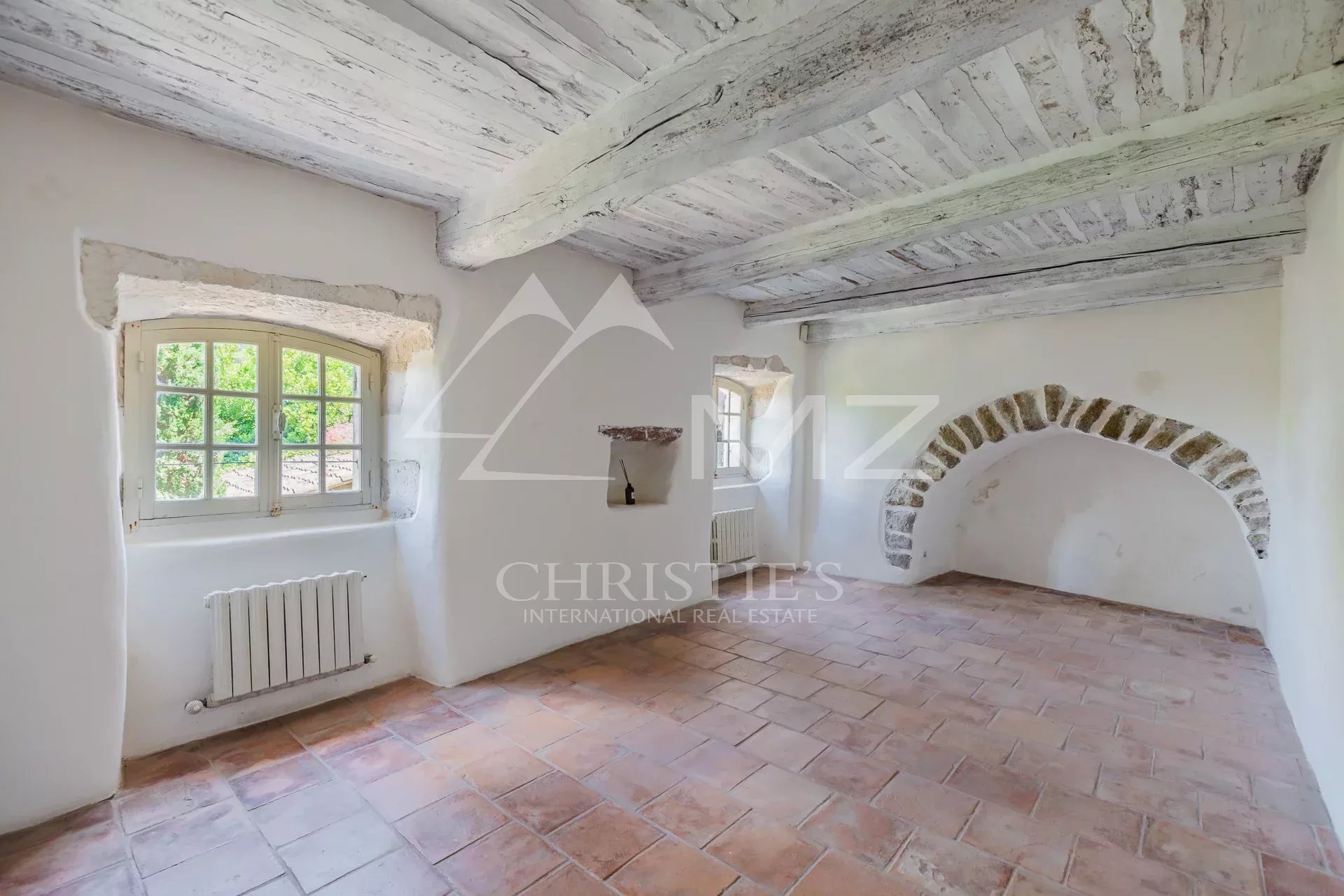 Interior of a renovated commercial space with exposed beams and terracotta floor in Ménerbes.