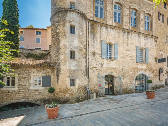 Immeuble de caractère à Ménerbes avec façade en pierre et espace commercial au rez-de-chaussée.