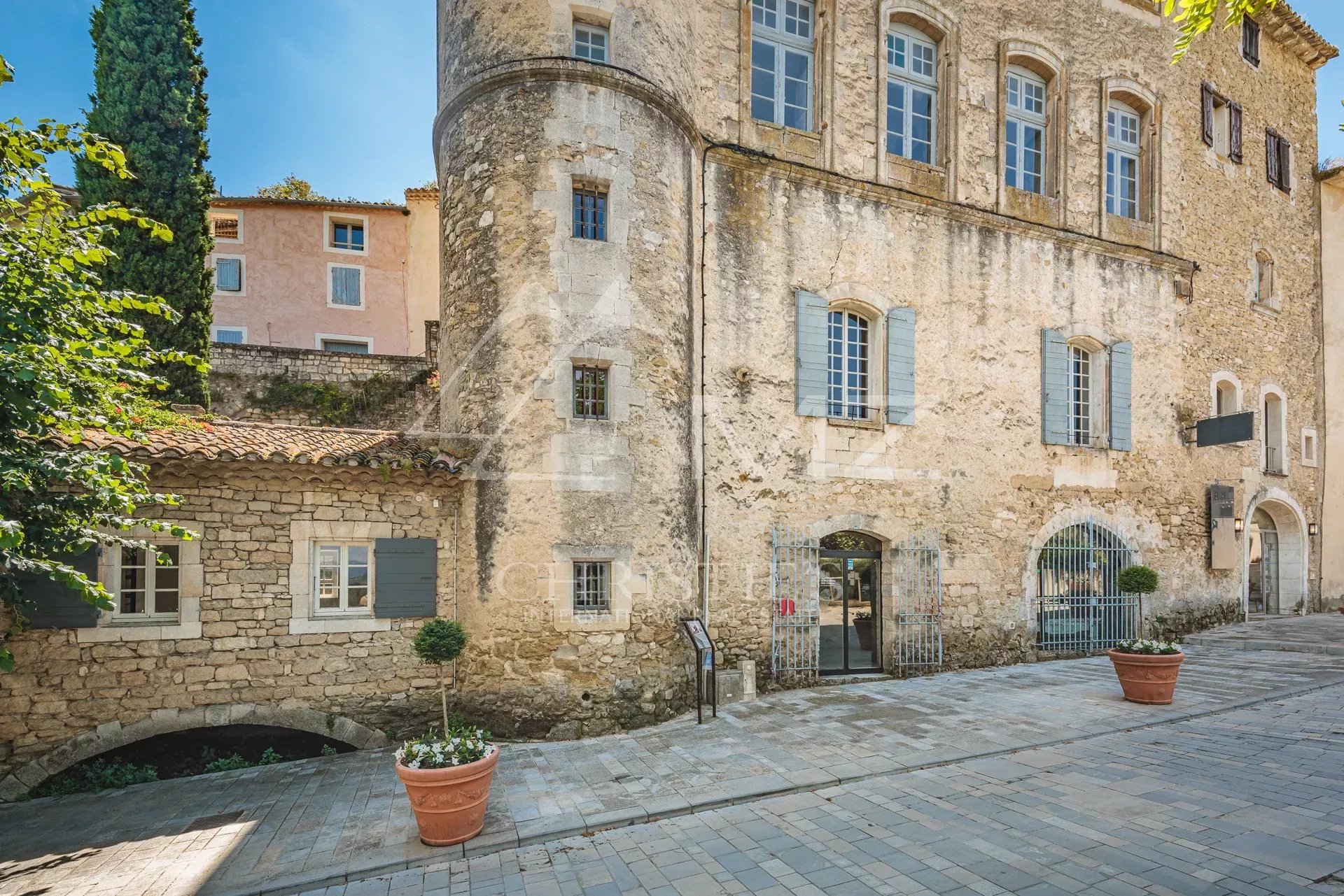 Character building in Ménerbes with stone facade and commercial space on the ground floor.