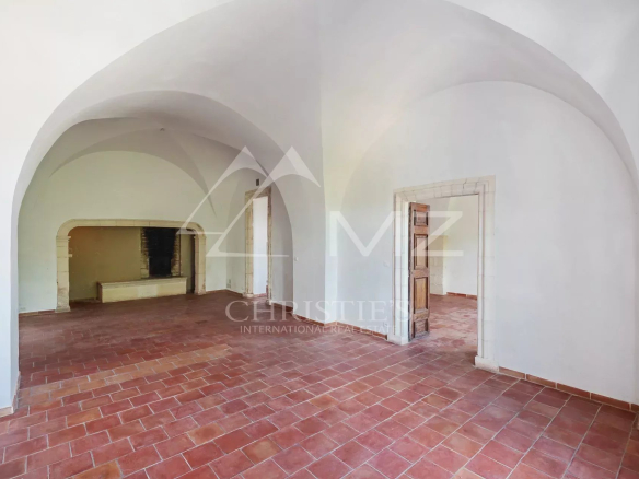 Interior of a renovated commercial space in Ménerbes with arches and a terracotta floor.