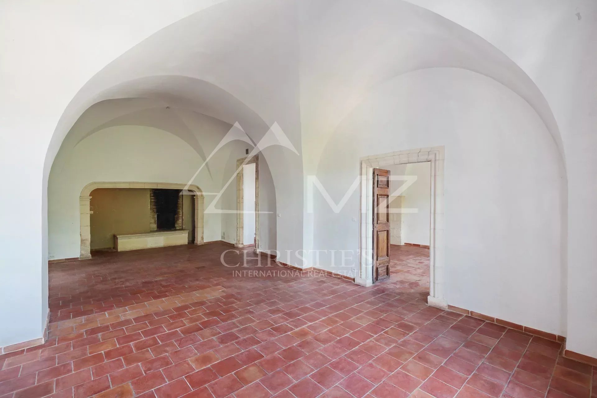 Interior of a renovated commercial space in Ménerbes with arches and a terracotta floor.