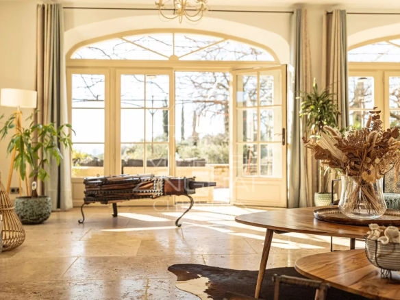 Intérieur d'une propriété provençale avec vue sur la campagne, décoré avec des plantes et du mobilier en bois.