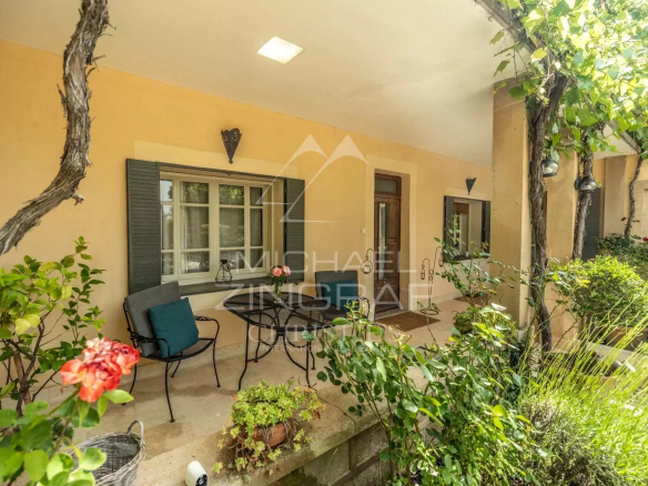 Terrasse d'une propriété provençale avec plantes et mobilier, vue sur le jardin.