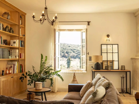Intérieur d'une propriété provençale avec un salon lumineux et vue sur la campagne.