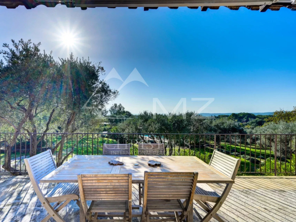 Terrasse en bois avec table et chaises, vue sur la campagne et les oliviers à Gordes.
