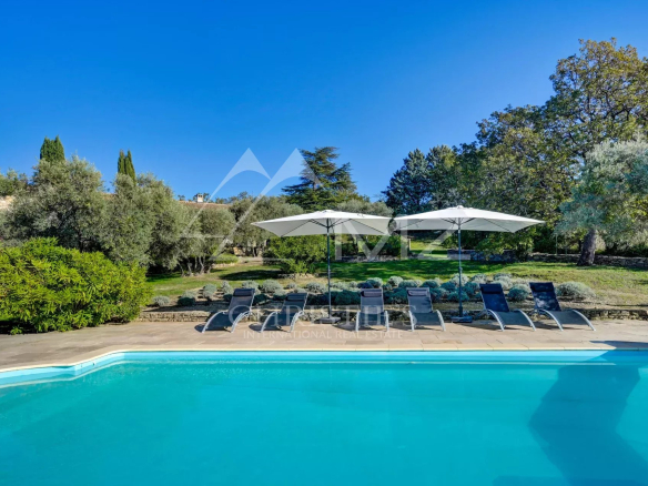 Piscine avec chaises longues et parasols dans un jardin ensoleillé à Gordes.