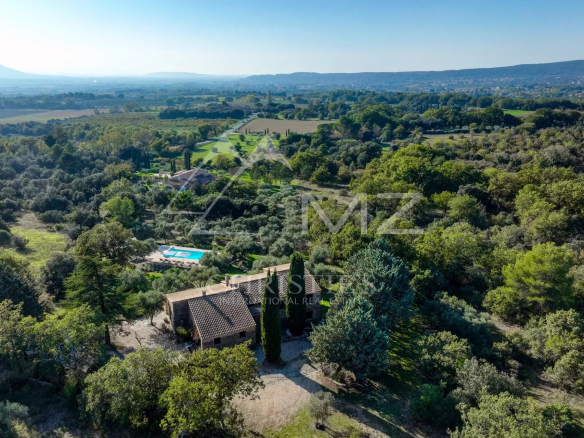 Vue aérienne d'une maison en pierre avec piscine entourée de verdure à Gordes.