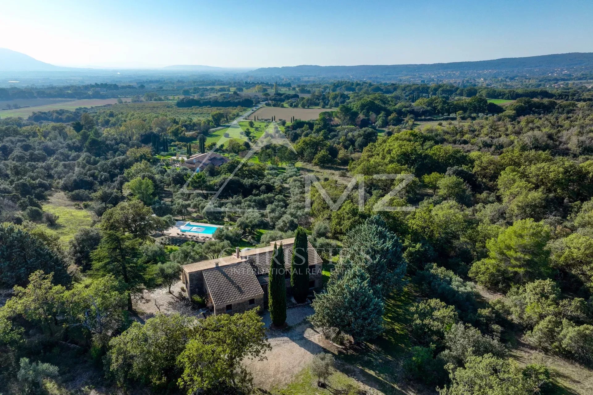Maison en pierre avec piscine à Gordes Vue aérienne d'une maison en pierre avec piscine entourée de verdure à Gordes.