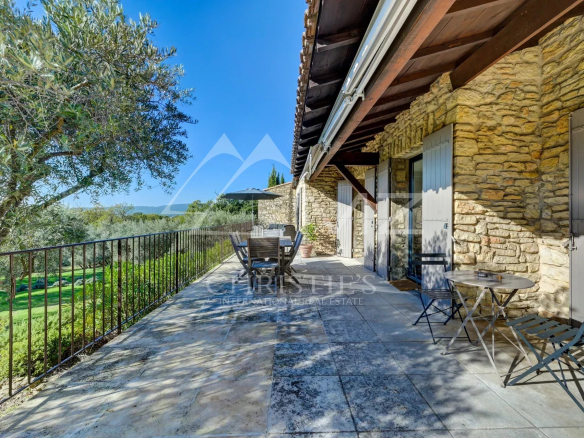 Terrasse d'une maison en pierre avec vue sur la campagne et mobilier extérieur à Gordes.