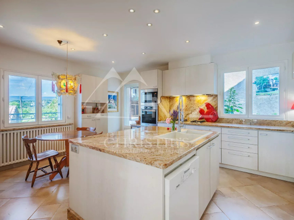 Cuisine moderne dans une maison spacieuse avec fenêtres offrant une vue sur l'extérieur.