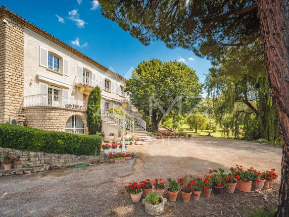 Stone house with flower garden and trees, panoramic view of nature.