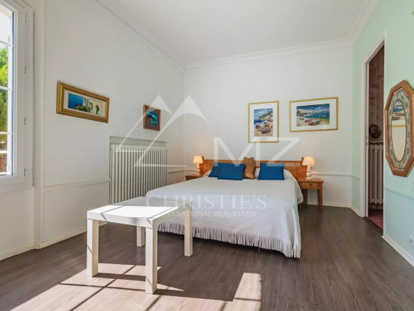 Chambre lumineuse avec lit double et table, décorée de tableaux, dans une maison à Apt.
