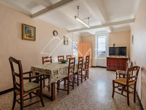 Salle à manger d'un mas du XIXe siècle à rénover, avec table et chaises en bois.