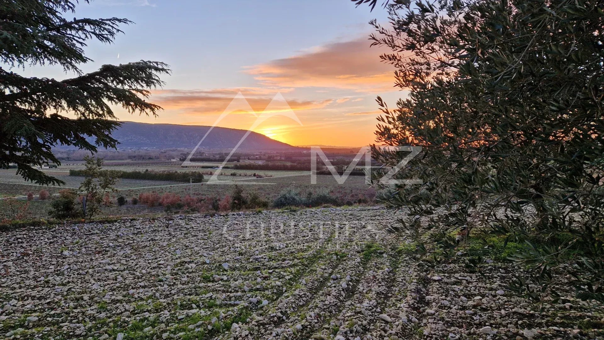 Coucher de soleil sur la plaine de Gordes Vue panoramique sur la plaine et les montagnes au coucher du soleil, avec des champs en premier plan.
