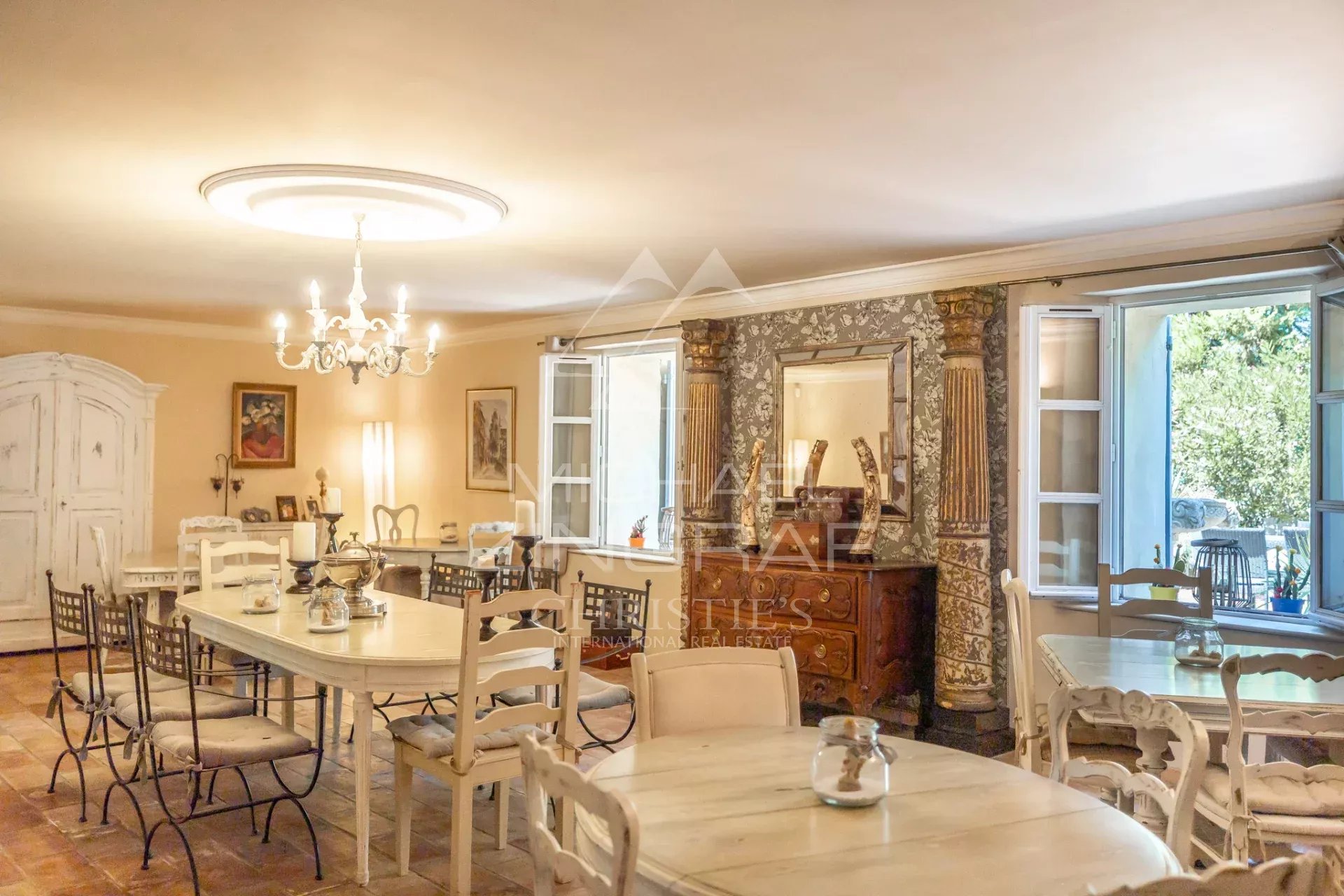 Intérieur d’un prieuré à L’Isle-sur-la-Sorgue Intérieur d'un ancien prieuré avec tables et chaises dans un cadre provençal.