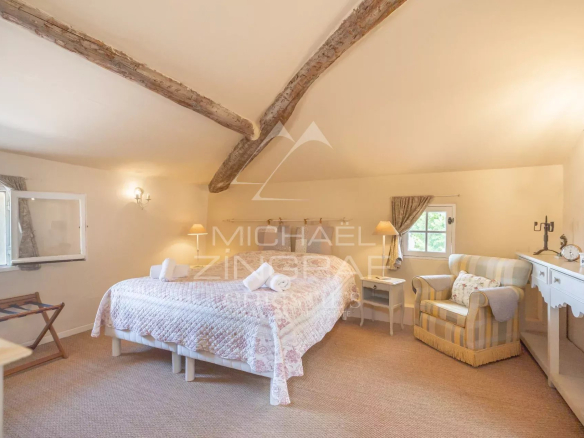 Chambre spacieuse avec lit double et fauteuil, décorée dans un style provençal.