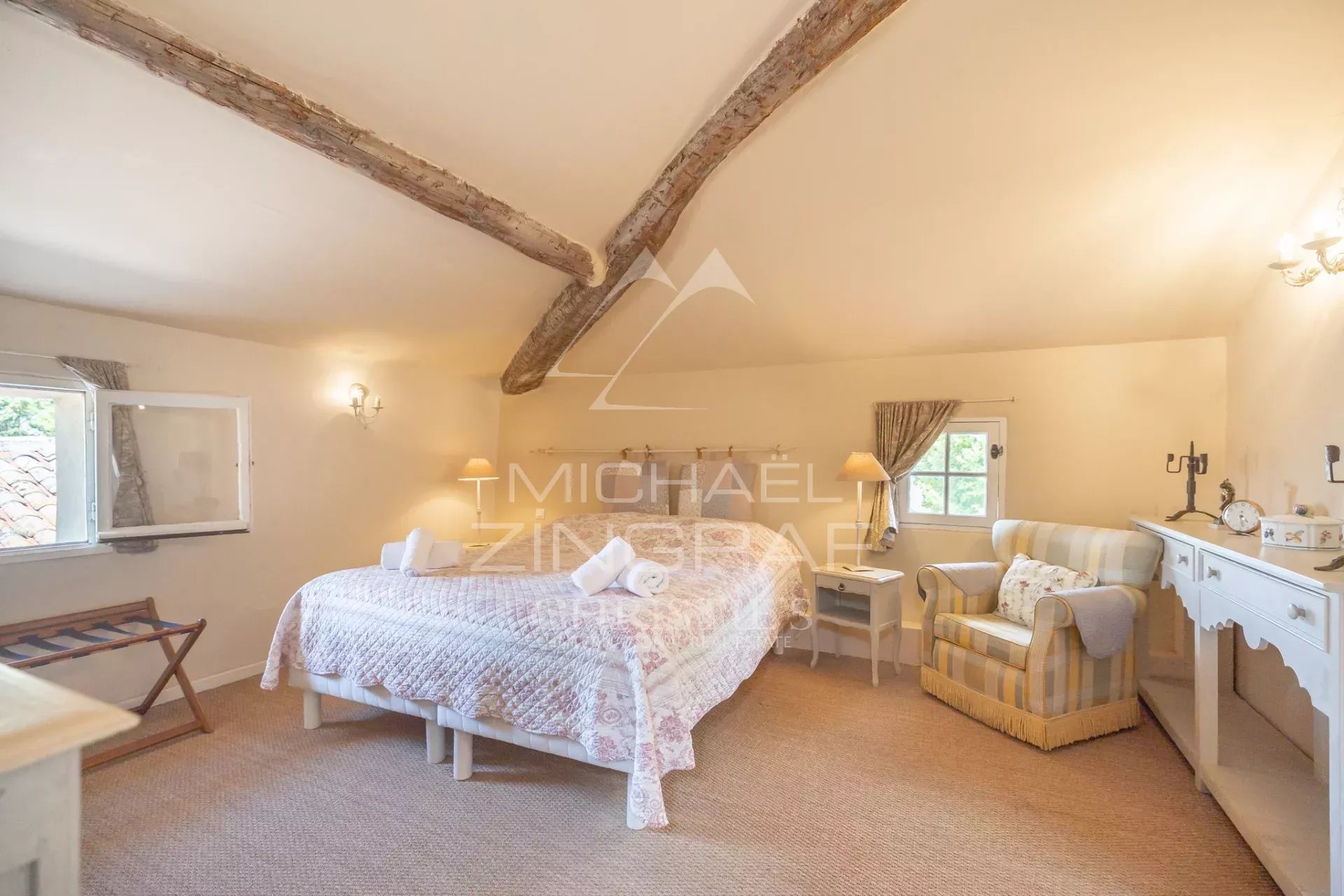 Chambre d’un domaine en Provence Chambre spacieuse avec lit double et fauteuil, décorée dans un style provençal.