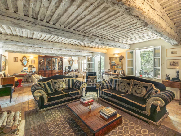Intérieur d'un salon avec des canapés en velours et des poutres apparentes dans un ancien prieuré.