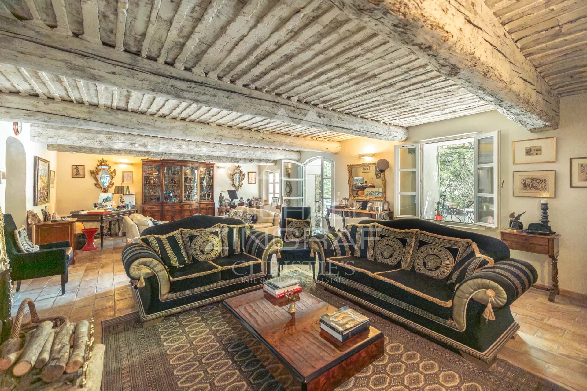 Salon d’un ancien prieuré à L’Isle-sur-la-Sorgue Intérieur d'un salon avec des canapés en velours et des poutres apparentes dans un ancien prieuré.