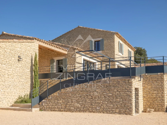 Contemporary stone villa in Gordes with views of the Luberon, surrounded by greenery.