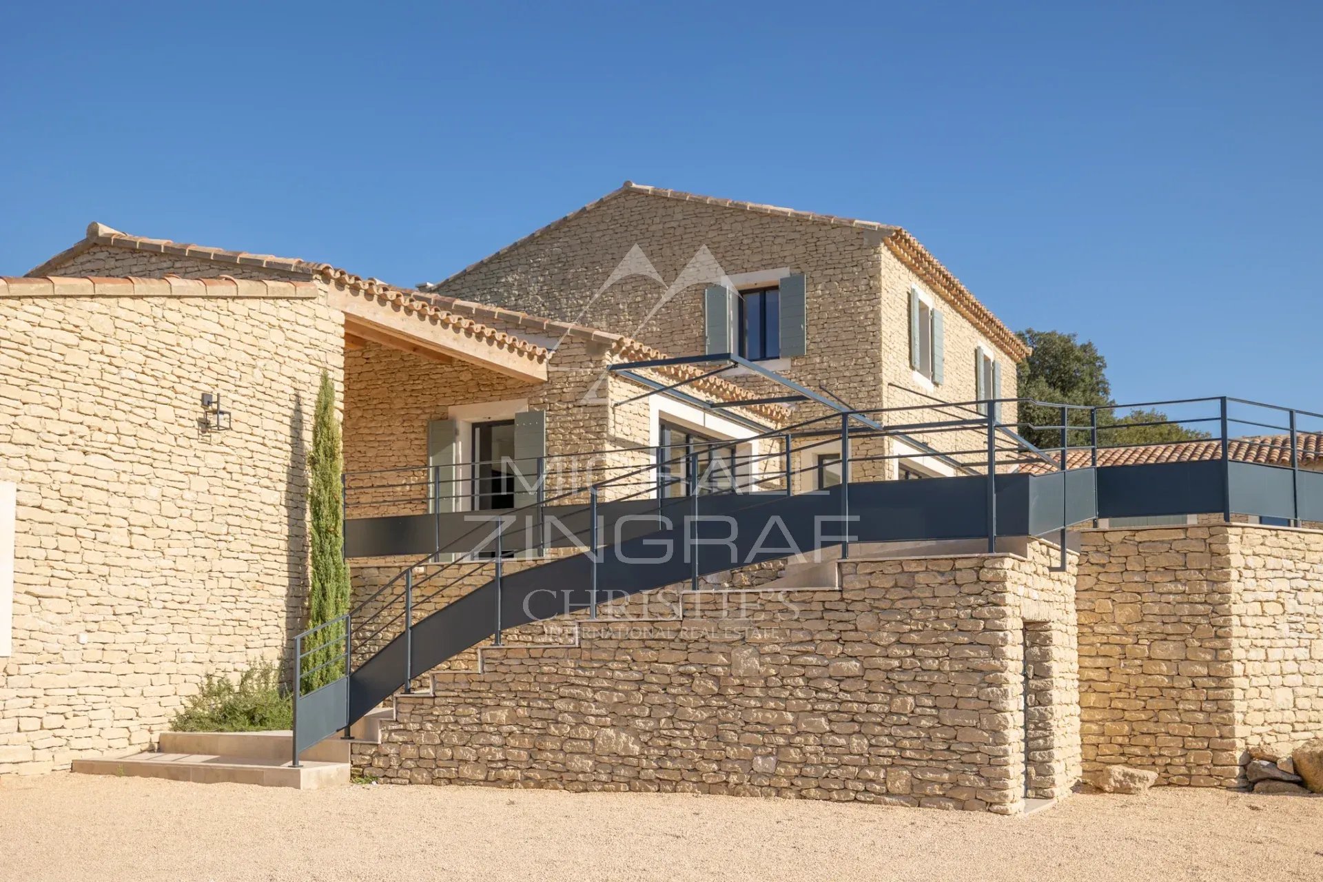 Contemporary villa in Gordes Contemporary stone villa in Gordes with views of the Luberon, surrounded by greenery.