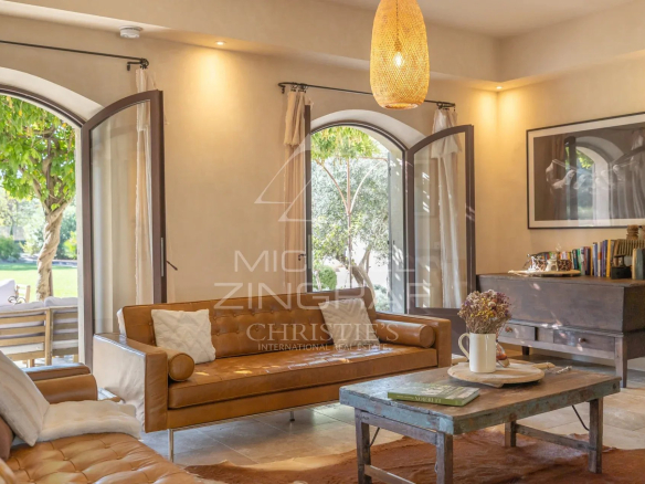Interior of a Provençal country house with open windows and a bright living room.