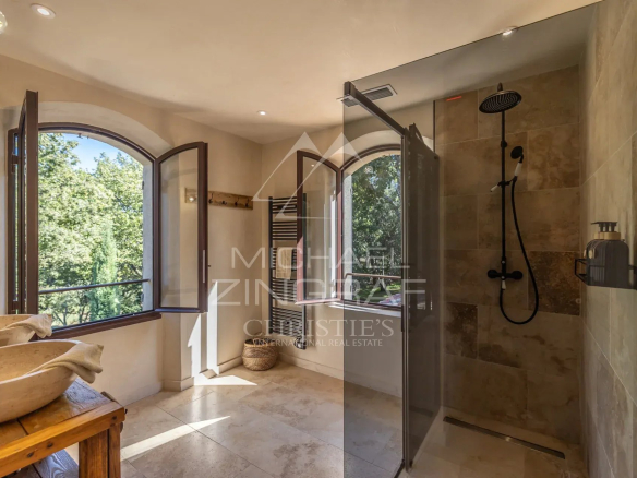 Modern bathroom with walk-in shower and windows opening onto nature.
