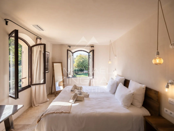 Room in a Provençal country house with open windows and a view of the garden.