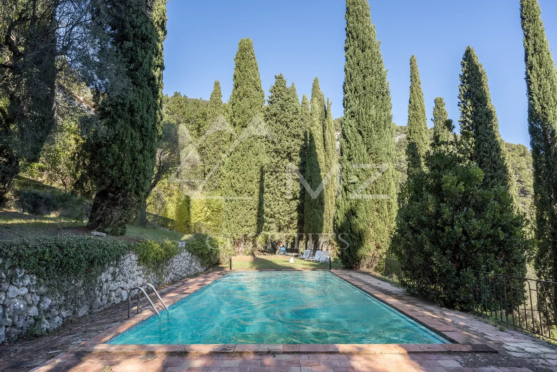 Swimming pool surrounded by cypress trees in a property in Tourrettes-sur-Loup.