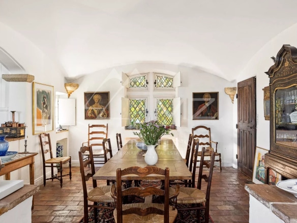 Dining room of a manor house in Tourrettes-sur-Loup with wooden chairs and paintings on the walls.