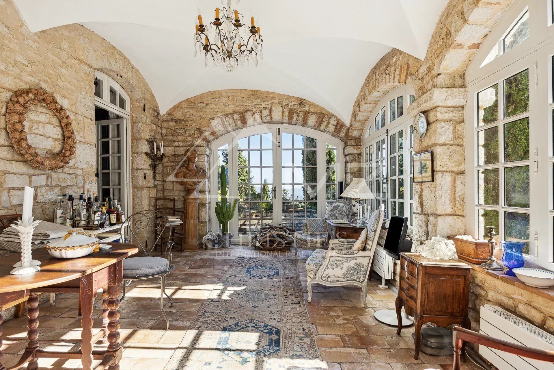 Interior of a manor house with stone walls, arched windows and elegant furnishings.
