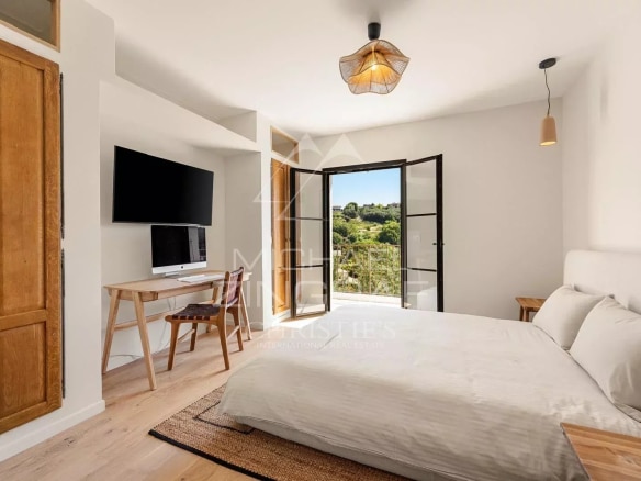 Chambre lumineuse avec vue sur le village de Saint Paul de Vence, décor moderne et chaleureux.