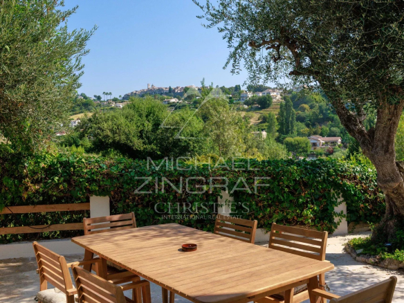 Vue panoramique sur le village de Saint Paul de Vence depuis une terrasse avec table en bois.