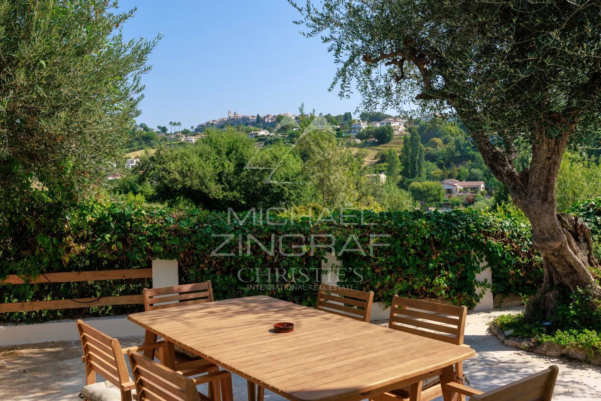 Vue sur Saint Paul de Vence Vue panoramique sur le village de Saint Paul de Vence depuis une terrasse avec table en bois.