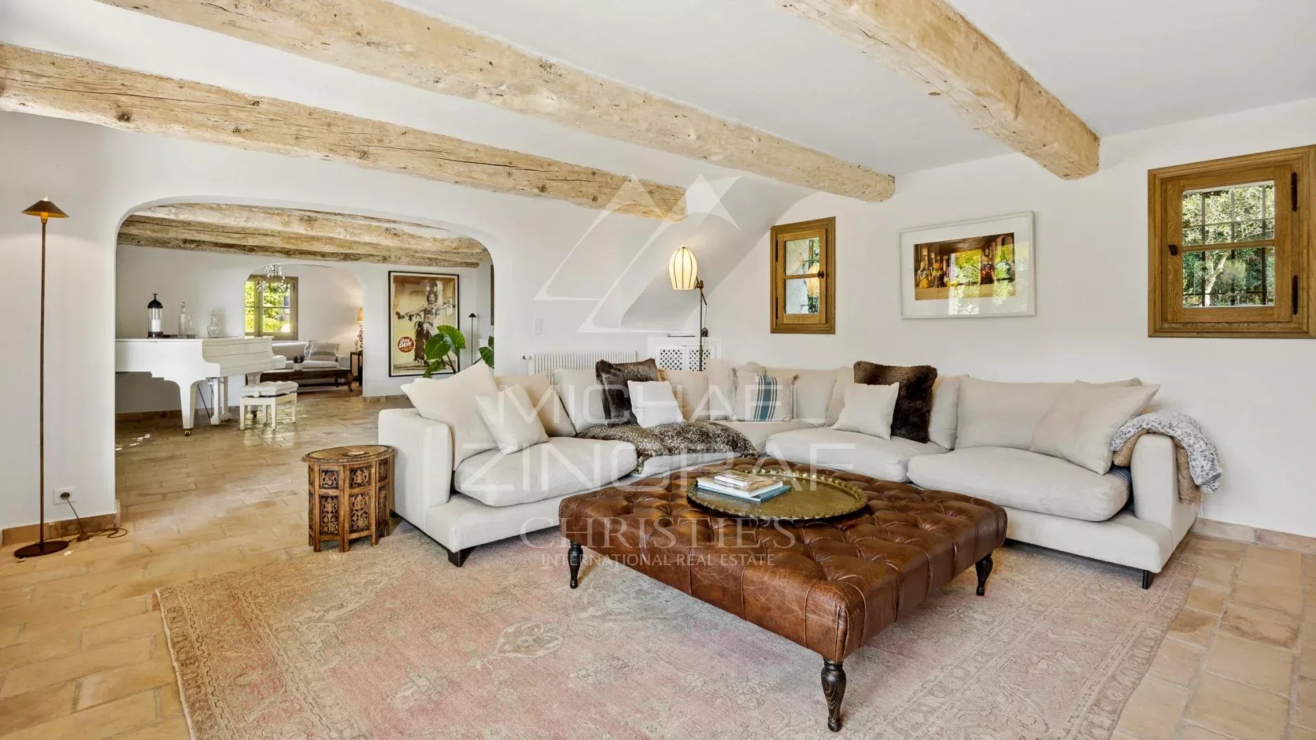 Intérieur d'une maison provençale rénovée avec un salon confortable et des poutres apparentes.