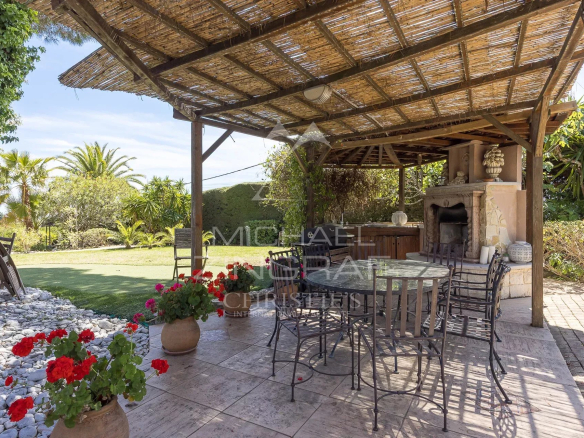 Terrasse en bois avec mobilier de jardin et barbecue, entourée de verdure dans une propriété à Saint-Paul-de-Vence.