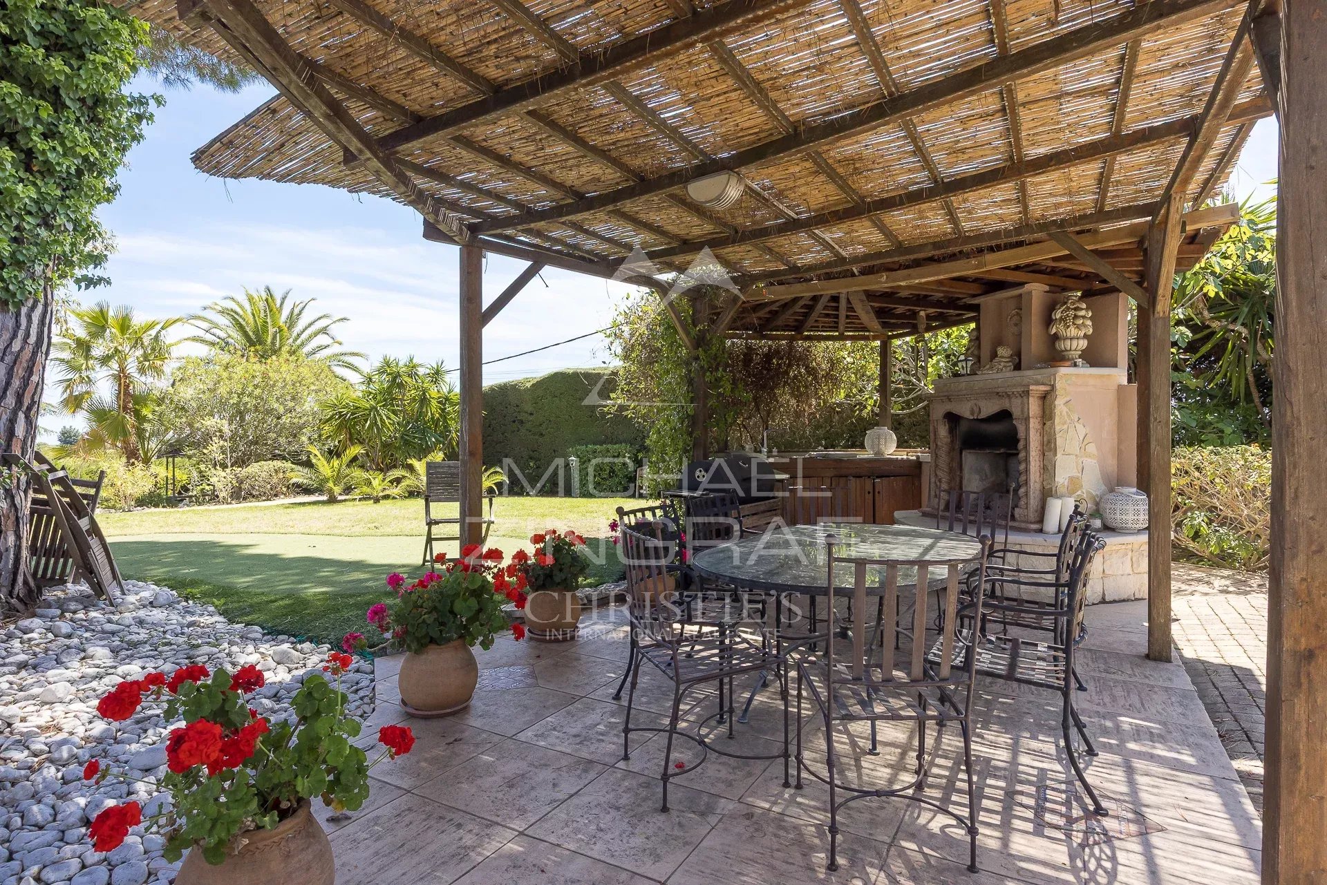 Terrasse d’une propriété néo-provençale à Saint-Paul-de-Vence Terrasse en bois avec mobilier de jardin et barbecue, entourée de verdure dans une propriété à Saint-Paul-de-Vence.